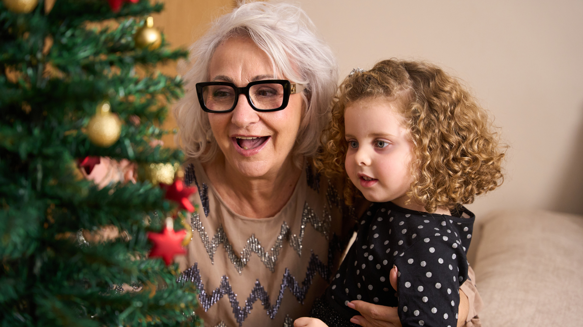 Grandmother and granddaughter decorating the christmas tree together, enjoying precious family moments during the festive season