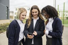 Teenage schoolgirls checking social media on smartphones