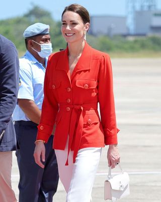 Kate Middleton wearing a red jacket and white trousers