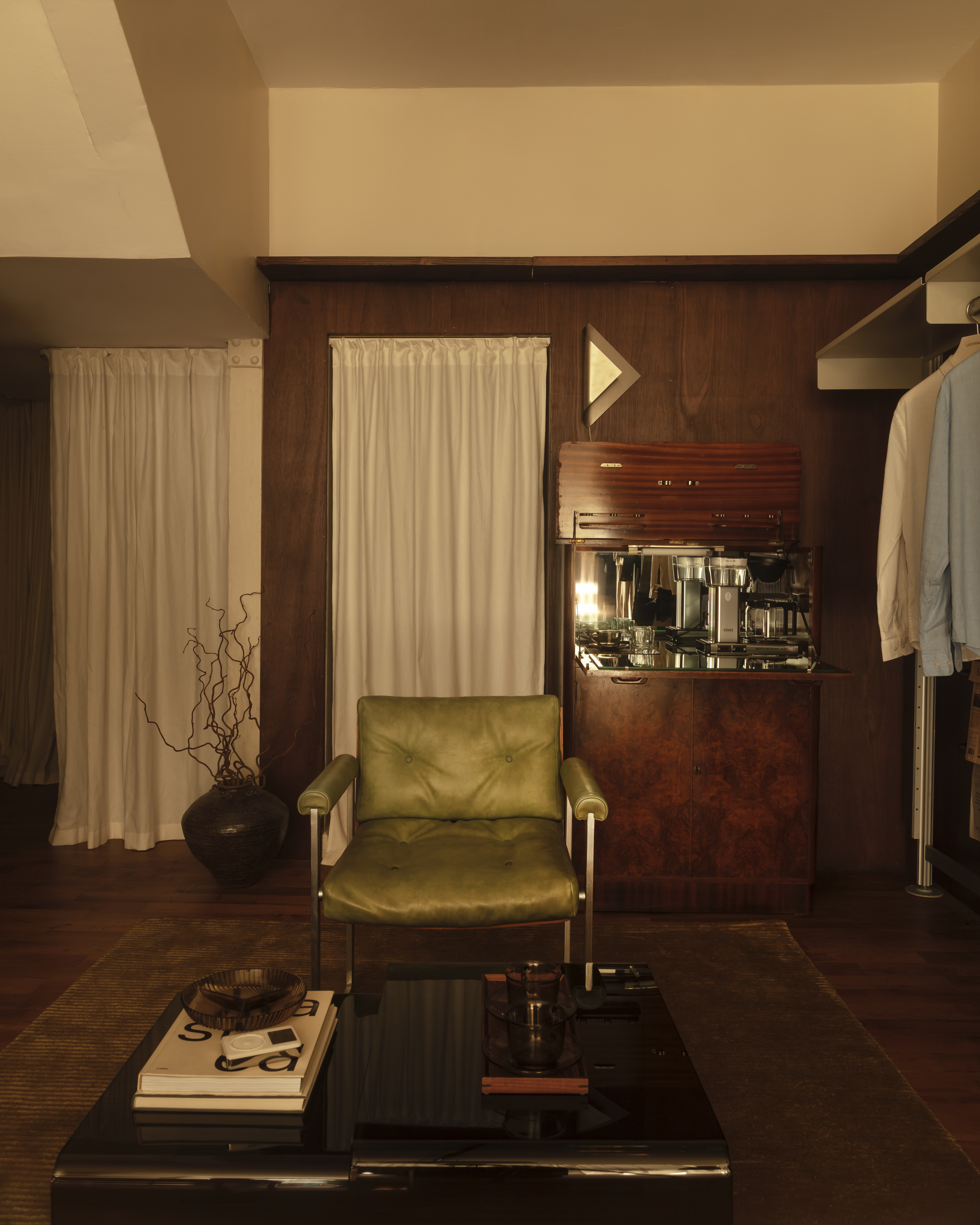 Different corners of a sleek menswear store clad in warm woods, beige drapery, and silver and mint green accents.