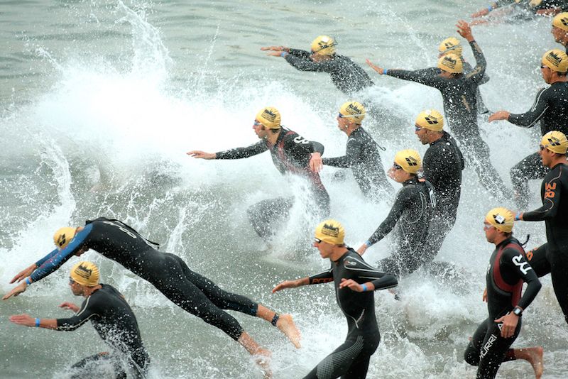 Triathletes at the start of a race, entering the water.