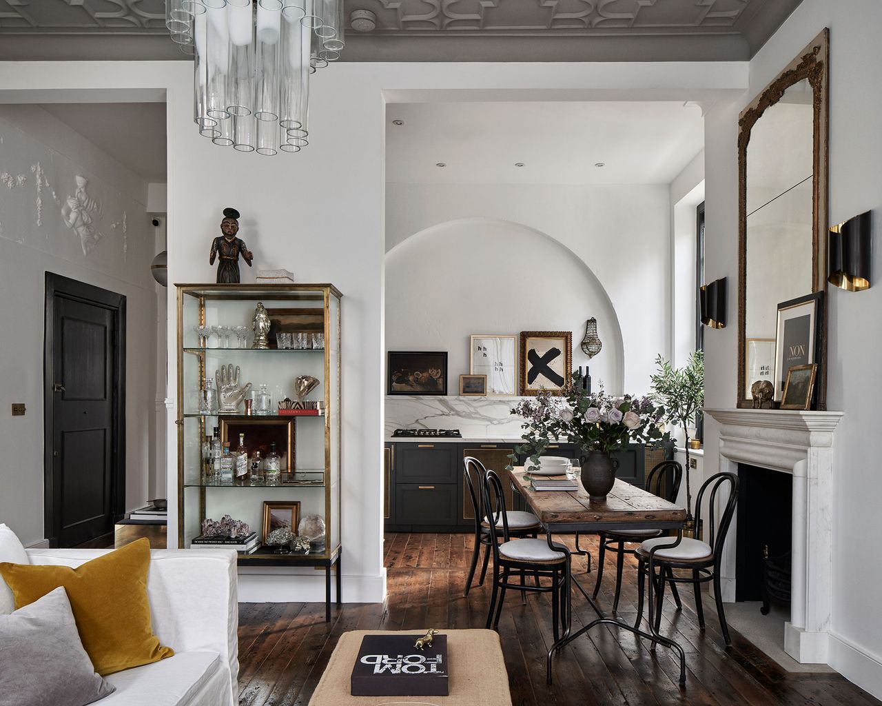 Open plan living room with wood floor, white walls and small kitchen