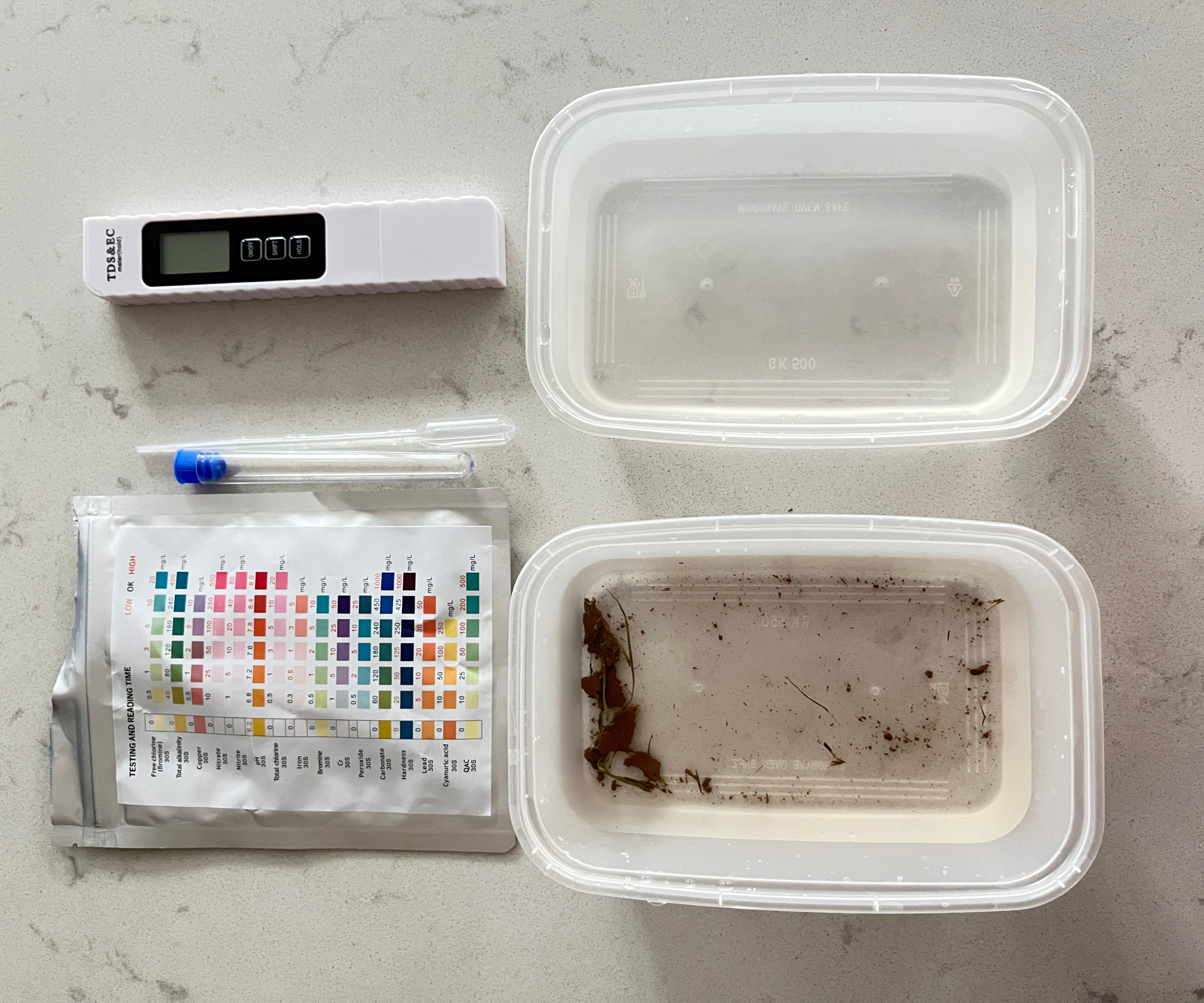 two containers of water, one clean, one dirty and two water testing kits next to them