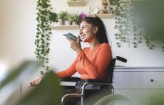 Woman in wheelchair talking on her smartphone, using speakerphone