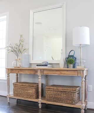 Rustic hallway with large white wall mirror, and rustic wood console table with baskets for storage.