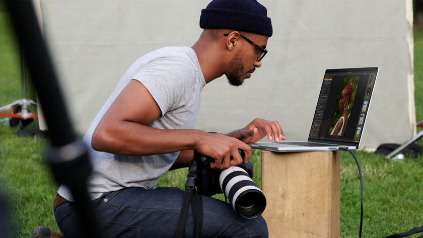 Man in beanie hat using an Apple MacBook Pro outside in a grassy area