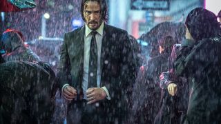 Keanu Reeves walking through crowded street in rain in John Wick 3