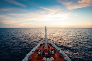 The bow of a boat in the foreground with the sea and horizon ahead