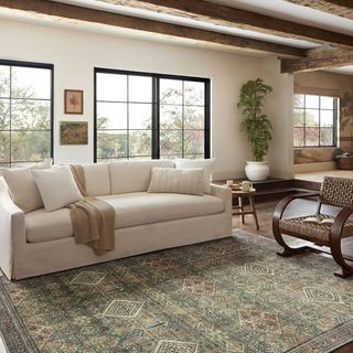 A farmhouse-style living room with a blue-green patterned area rug and a white couch