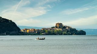 A photo of a lake overlooked by a hilly Italian village