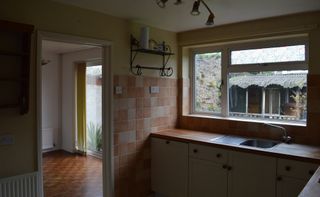 Georgia Broome kitchen: 'before' shot with terracotta wall tiles and yellow wall