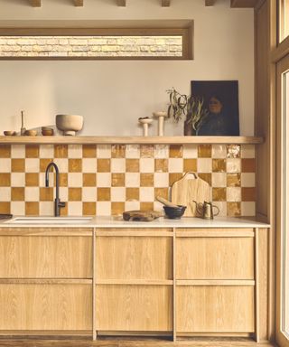 A wood kitchen with an earth-toned checkerboard tile backsplash