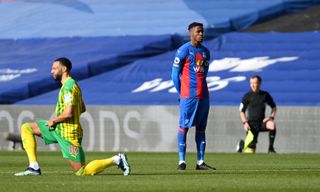 Crystal Palace’s Wilfried Zaha stands while players take a knee