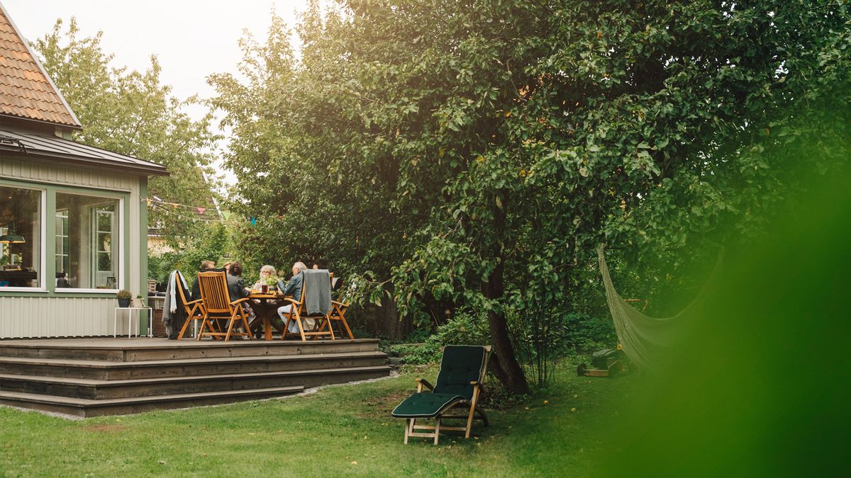 ard Projects to Complete in May | family sitting around a table on the patio in a large backyard