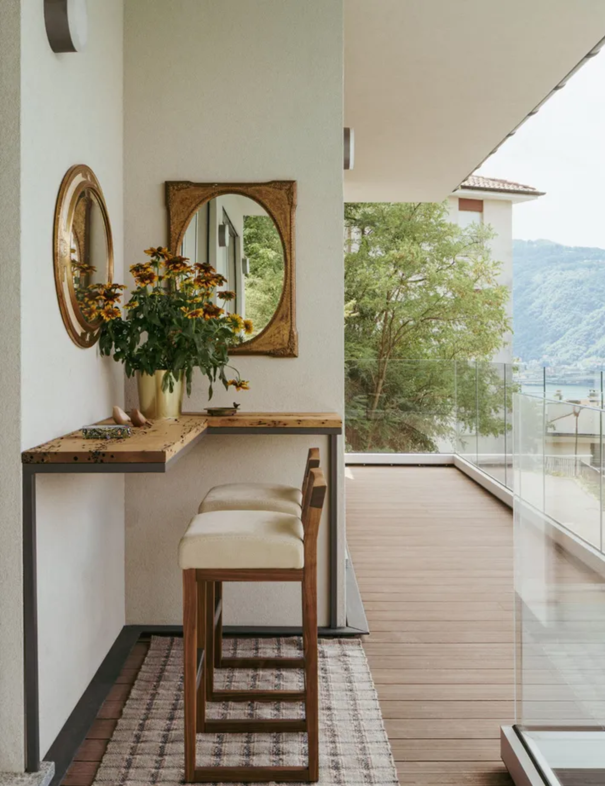 Wooden balcony area featuring two bar stools and view of lake
