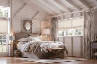 Drapes in a neutral/beige bedroom with slat white walls and light area rug over wooden floors