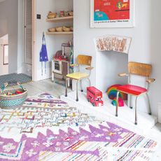 A playroom with a patterned colourful Berber-style rug and rattan baskets filled with toys