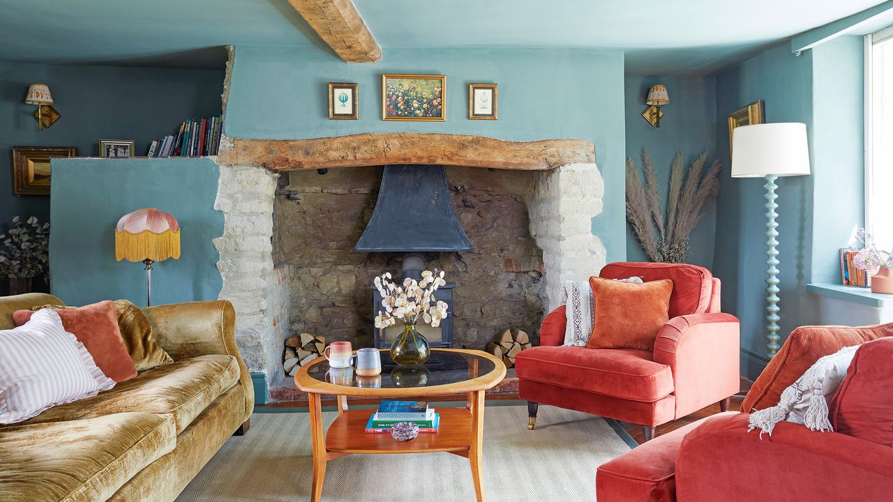 colour drenched blue living room with original fireplace with log burner and red velvet armchairs and yellow sofa