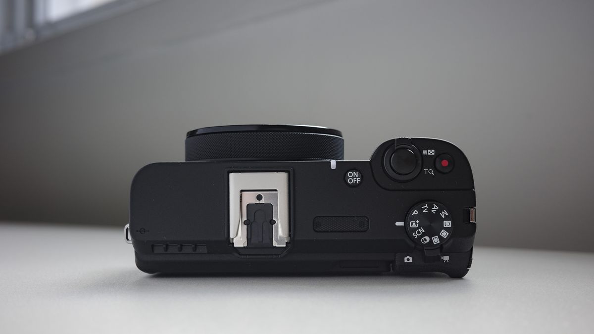 Top plate of the Canon PowerShot V1 compact vlogging camera on a white desk, lens retracted
