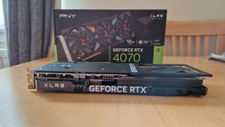 PNY GeForce RTX 4070 lying horizontally on a table in front of its box
