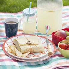 Check picnic blanket with coffee, juice and fruit
