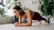 Woman setting up for plank rows exercise at home, smiling on floor