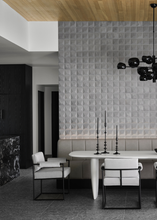 A large dining room with a tiled wall and dark decorative accents