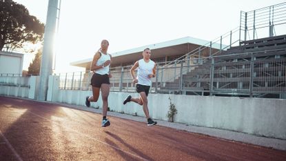 Best running watch: Pictured here, two athletes running on a track during sunrise
