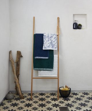 a wooden ladder leant against the wall with towels hanging over