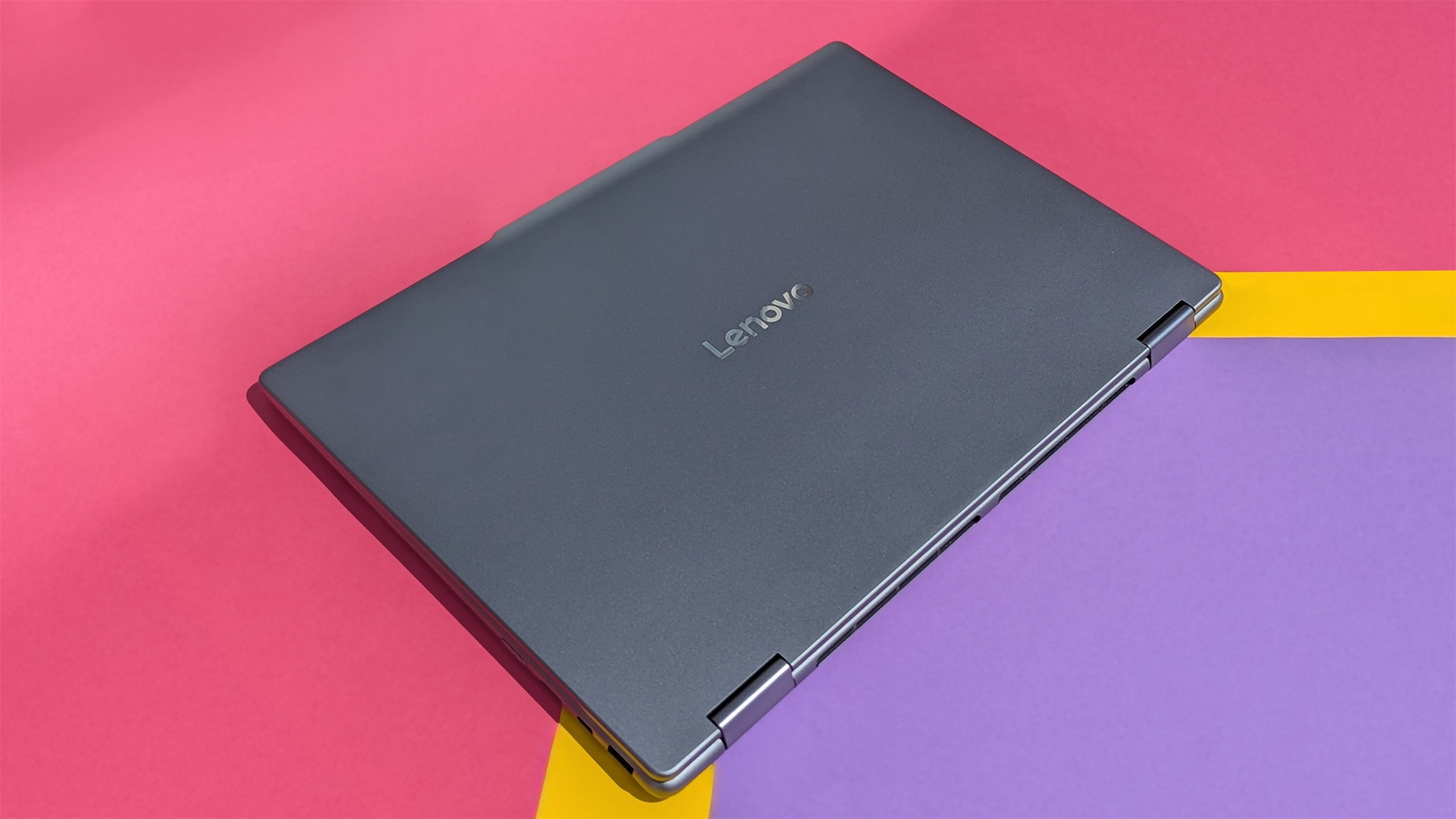 Lenovo Yoga 7i 16 (Gen 10) laptop with its lid closed on pink, yellow, and purple card.