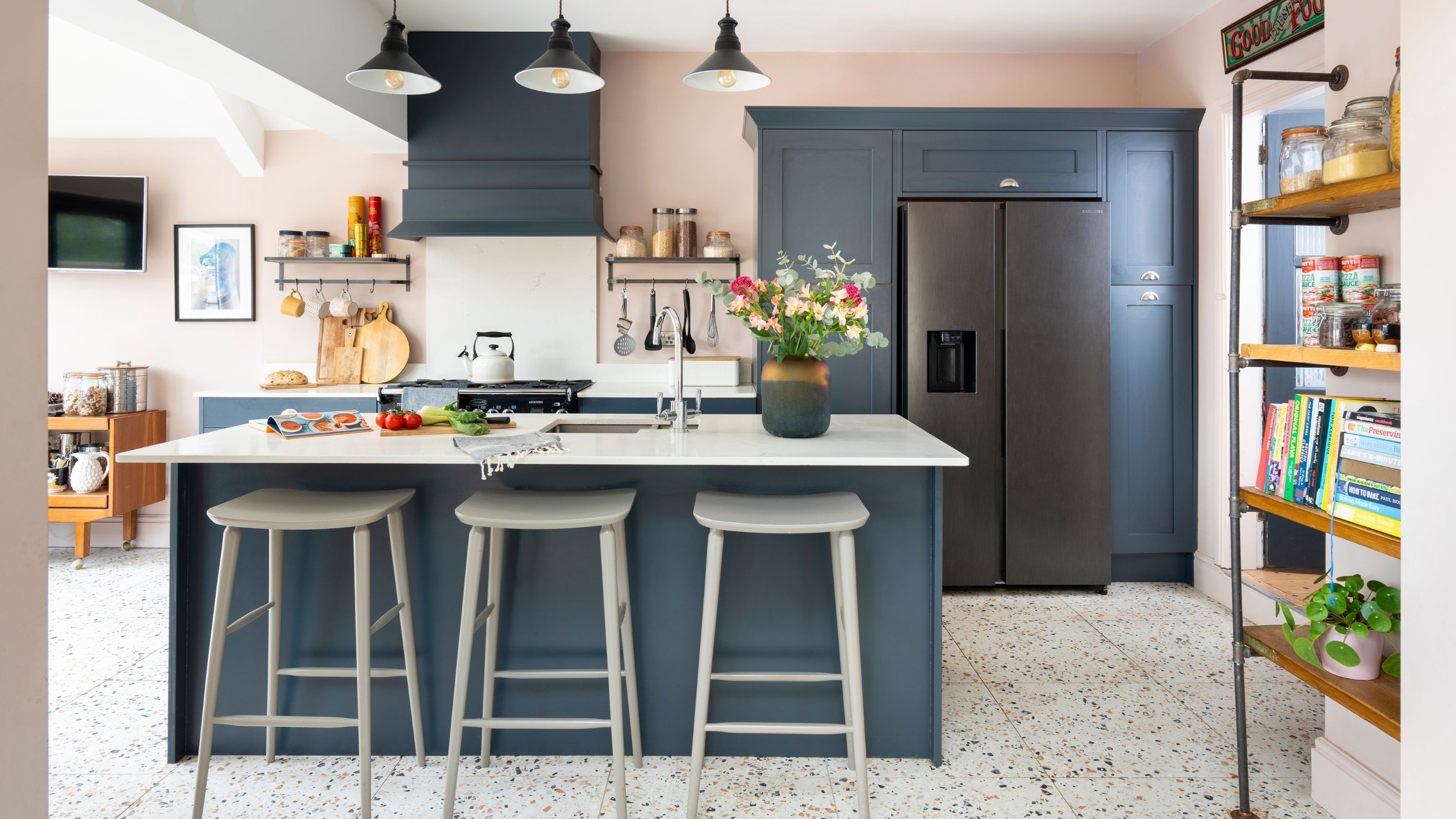 Pink painted kitchen with blue cabinets and a matching blue kitchen island, and terrazzo tiled floor