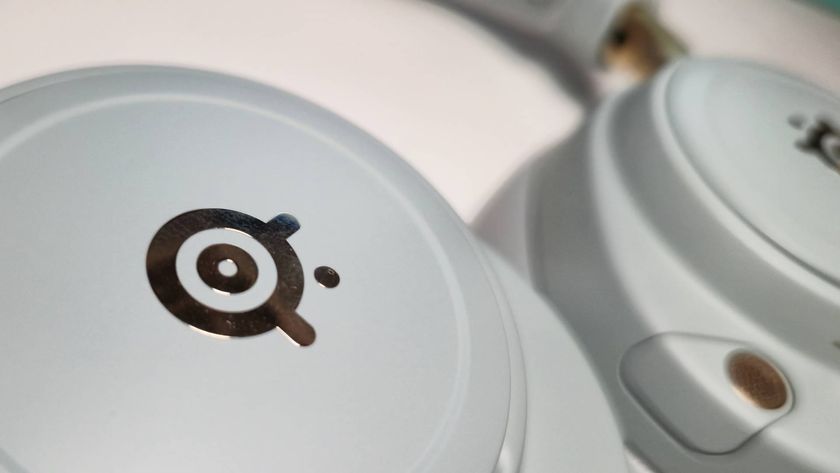 Photo of a close up of the gold SteelSeries logo on the earcup of the Arctis Nova Elite headset in Sage Gold.