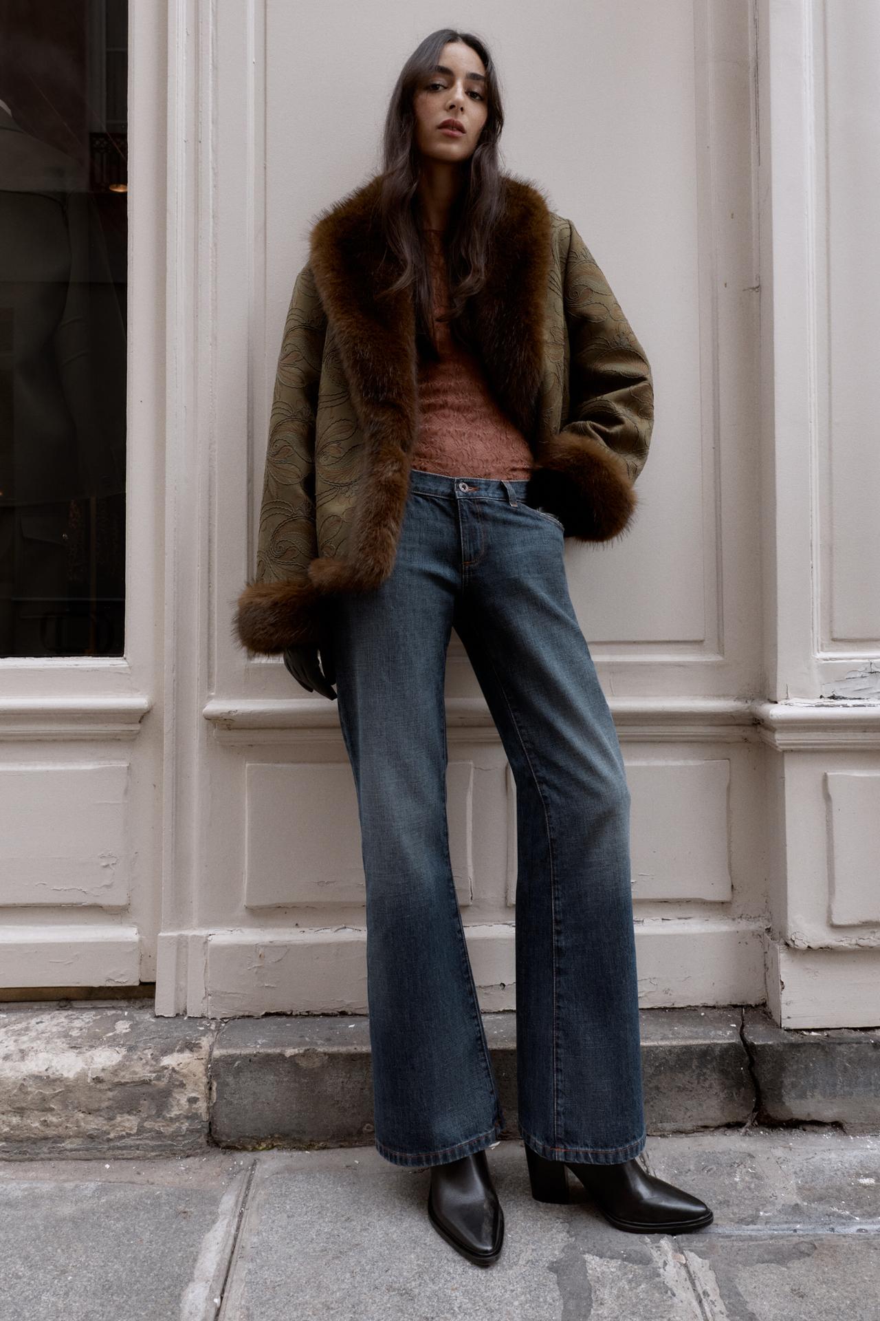 Woman wers longsleeve mauve shirt and jacket with faux fur trimmings and lining, low cut boot rise jeans, and black heels.