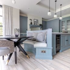 blue kitchen with banquette seating, globe lights, storage solutions, large kitchen island