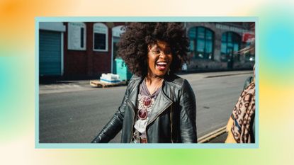 A side-view shot of a beautiful mid-adult woman smiling and laughing while walking down the street.