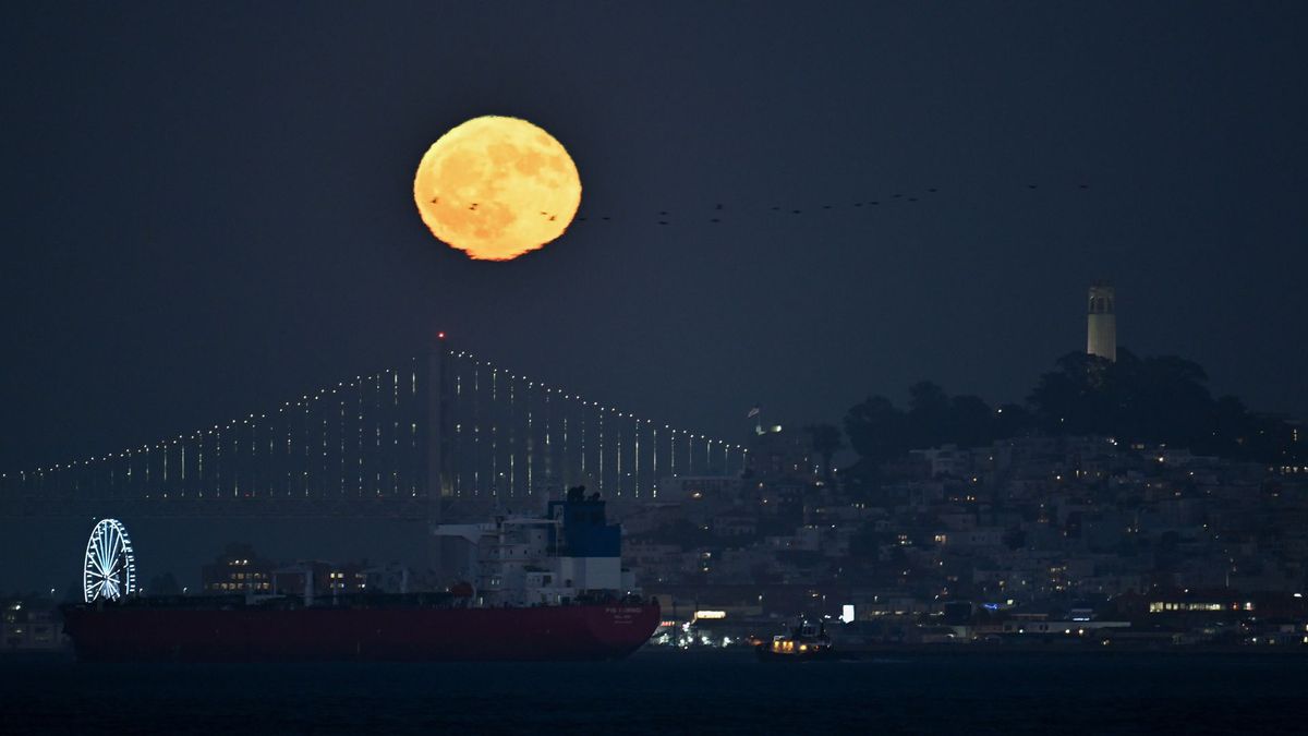 Una luna naranja brilla sobre el puente Golden Gate en San Francisco por la noche.