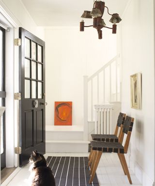 white hallway with chairs, artwork and dark painted door