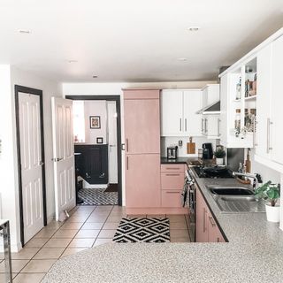 After view of Pink Frenchic painted kitchen cupboards with black and white kitchen rug