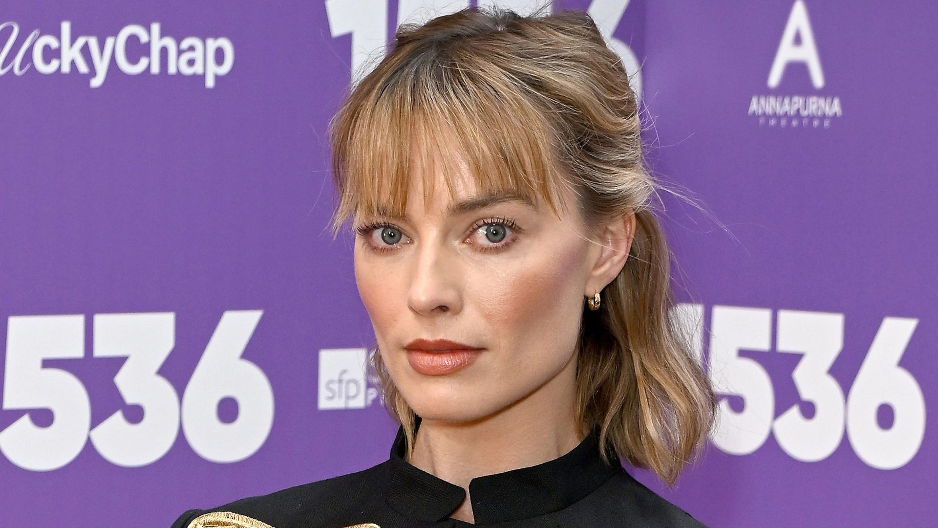 Margot Robbie pictured with almond blonde hair and a fringe on a red carpet