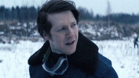 A man stands in a snowy field looking over his shoulder