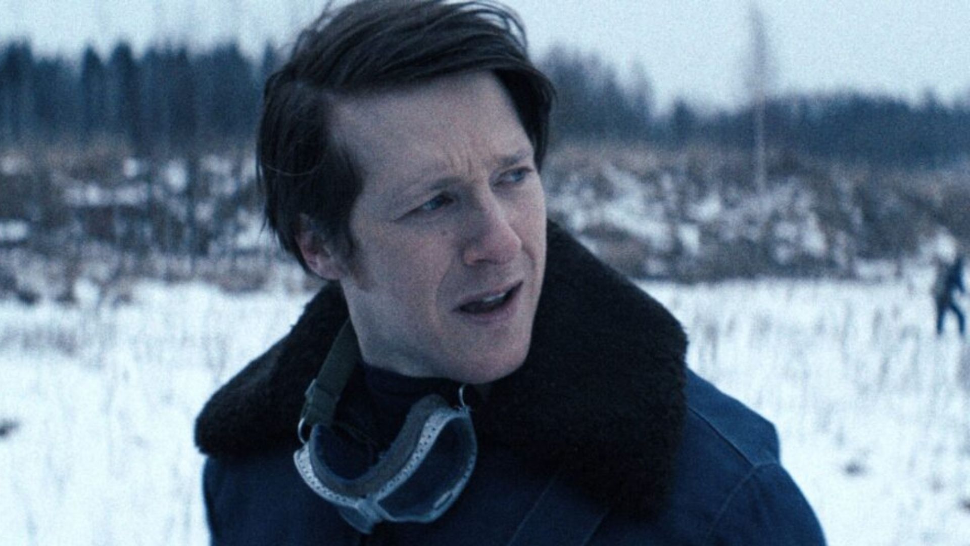 A man stands in a snowy field looking over his shoulder