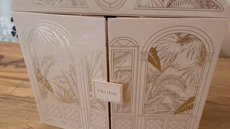 An animated GIF of a person opening the doors of the Tropic 24 Days of Pure Imagination beauty advent calendar to reveal the drawers inside