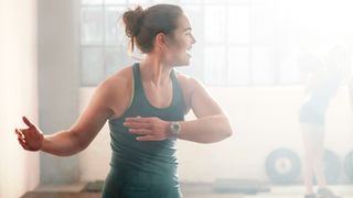 Woman warming up in gym, twisting her body to one side