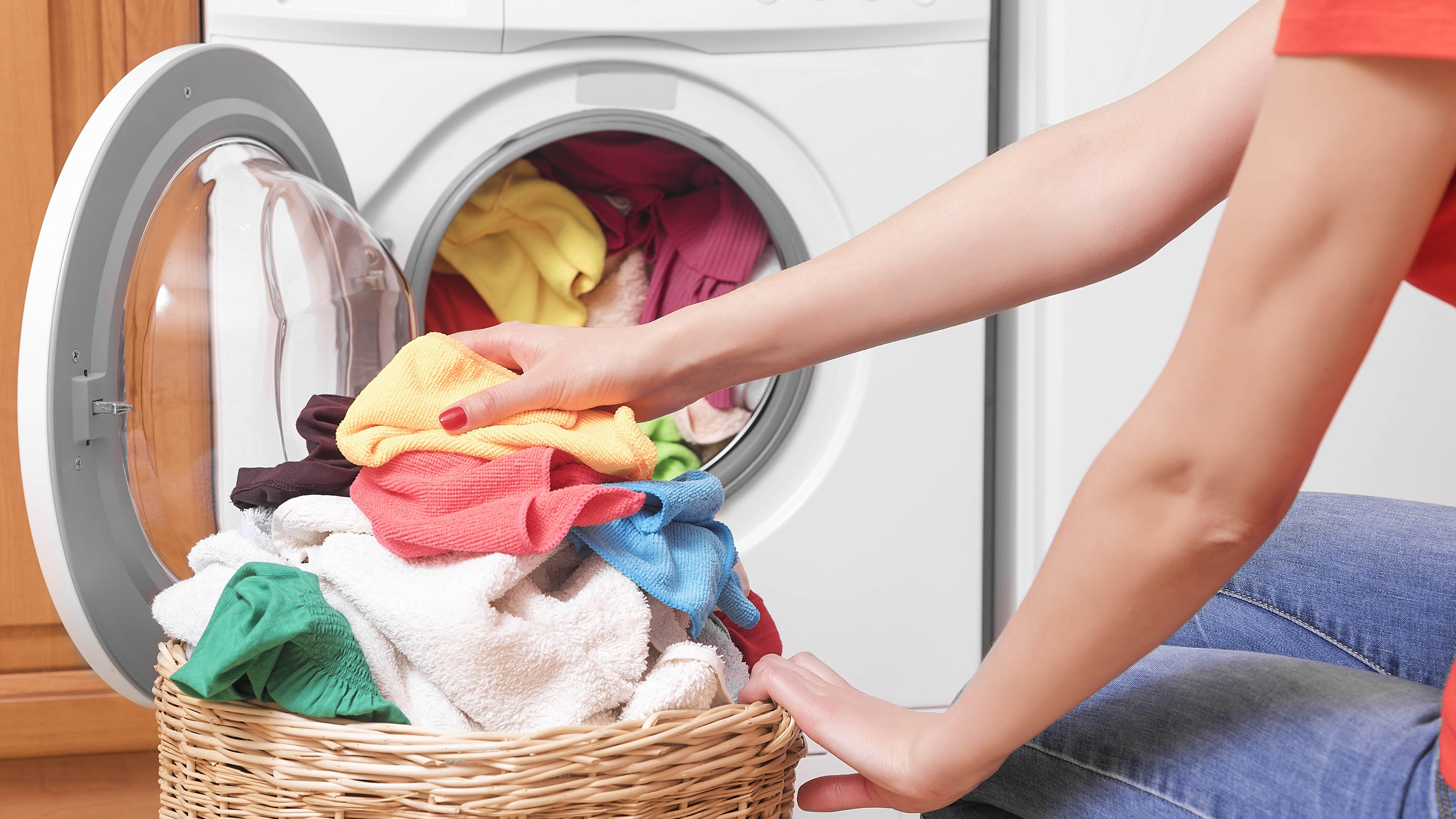 Person kneels and loads a washing machine