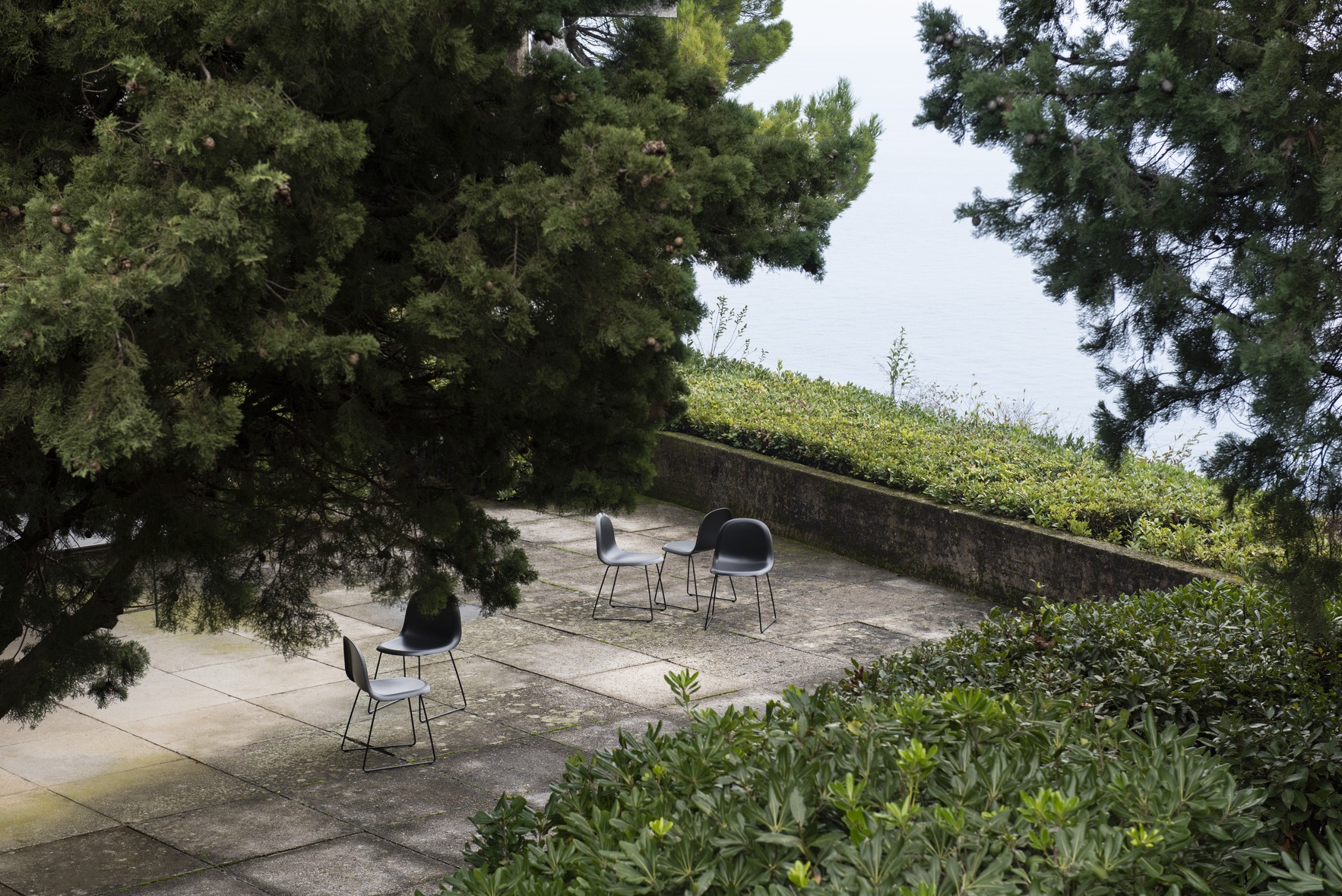 Paved patio with tree and recycled plastic garden chairs