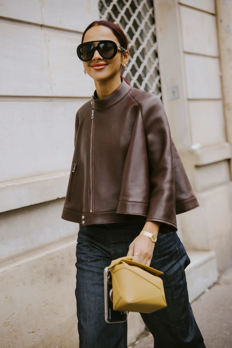 a new york fashion week guest wearing a chocolate brown leather jacket and jeans