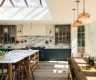 A blue and wood kitchen with off-white walls and marble countertops