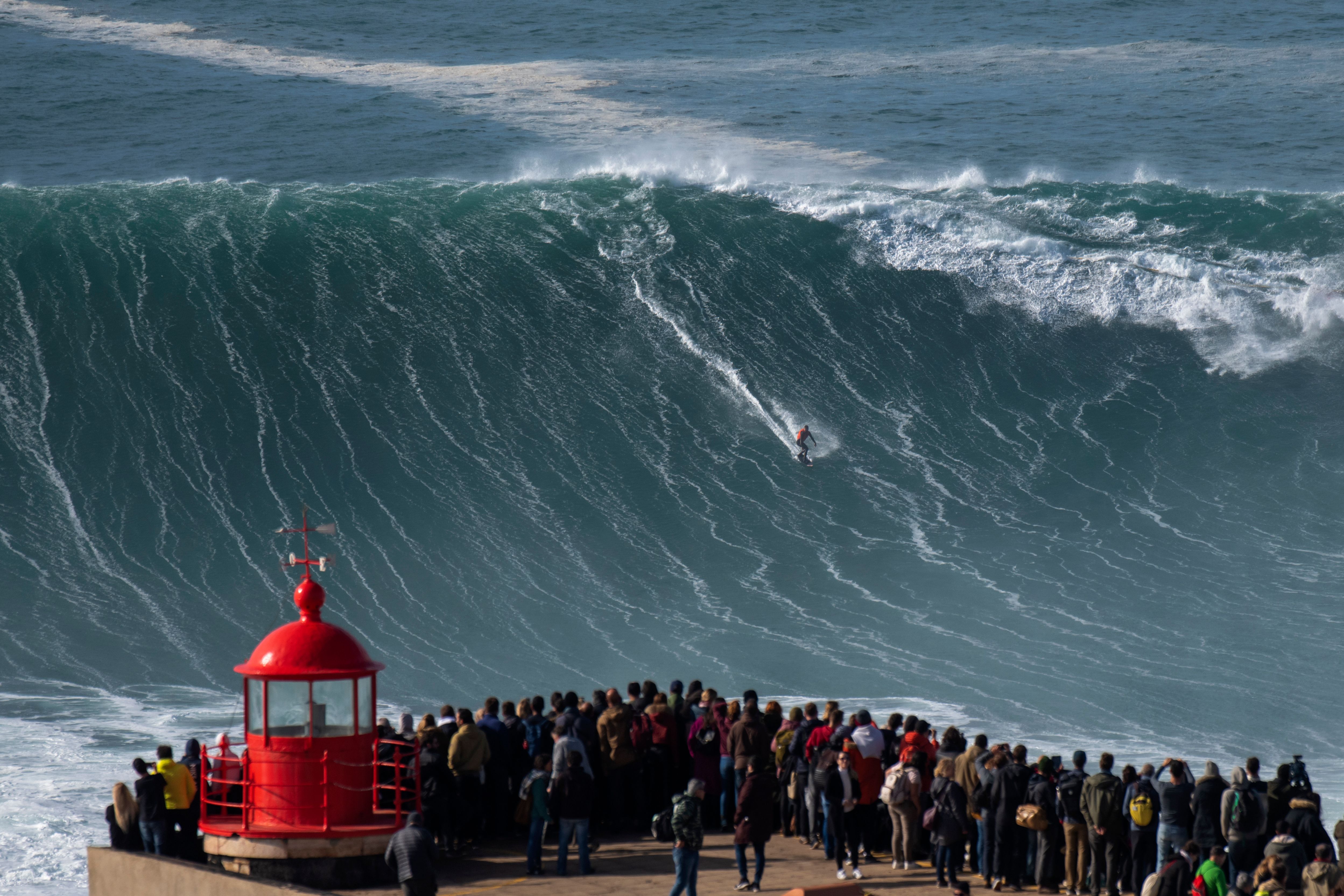 Onlookers watch as a surfer takes on a massive wave in Nazare, Portugal