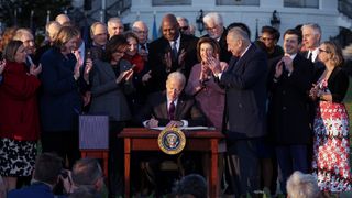 U.S. President Joe Biden signs the Infrastructure Investment and Jobs Act as he is surrounded by lawmakers and members of his Cabinet during a ceremony on the South Lawn at the White House on Nov. 15, 2021 in Washington, DC.