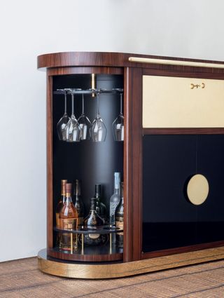 A 1950s-inspired bar cart in brown and black for Clos19 with an open side stocked with a selection of Clos19 spirits and champagne glasses.
